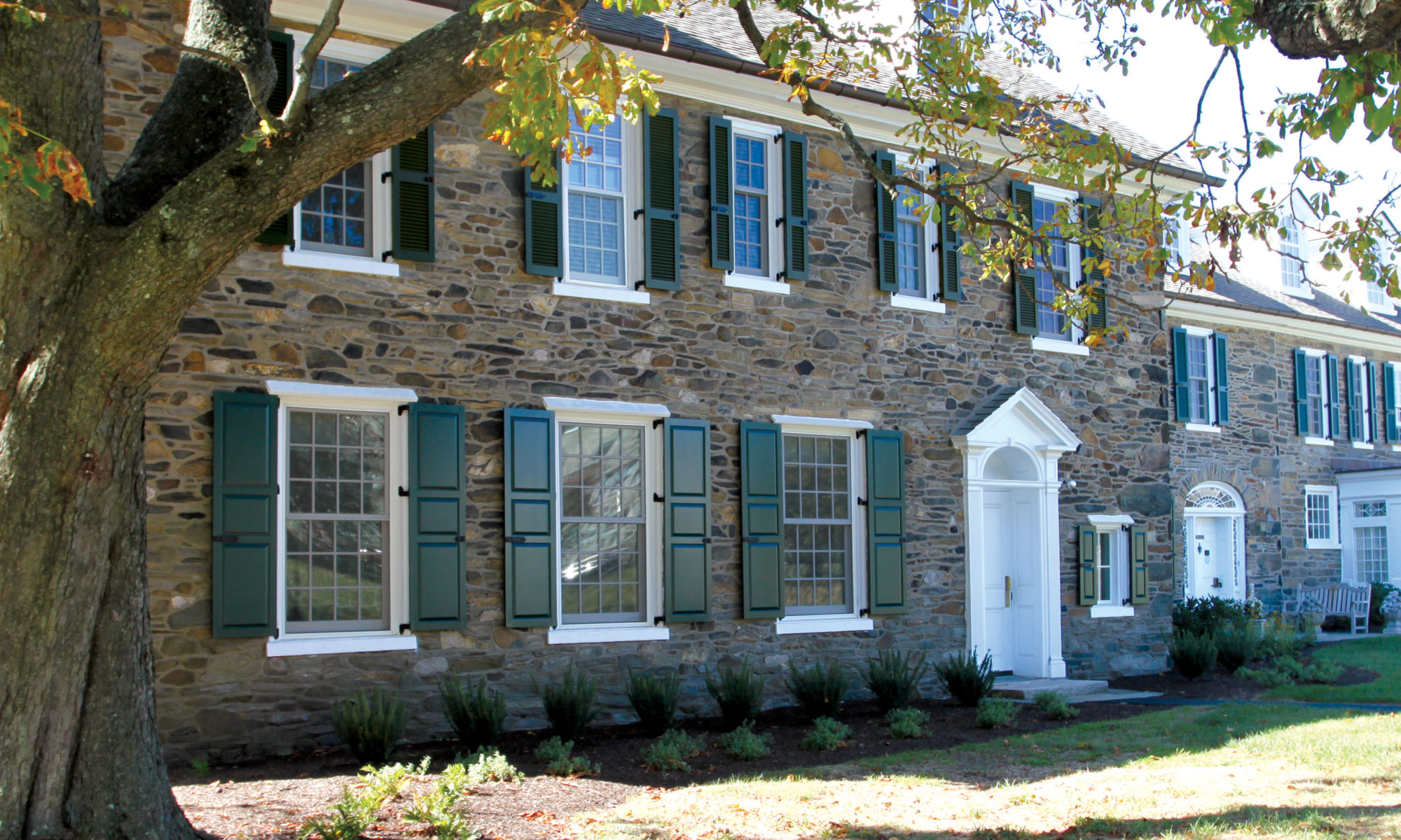 Atlantic Premium Shutters arch panel and louver shutters on stone Colonial home